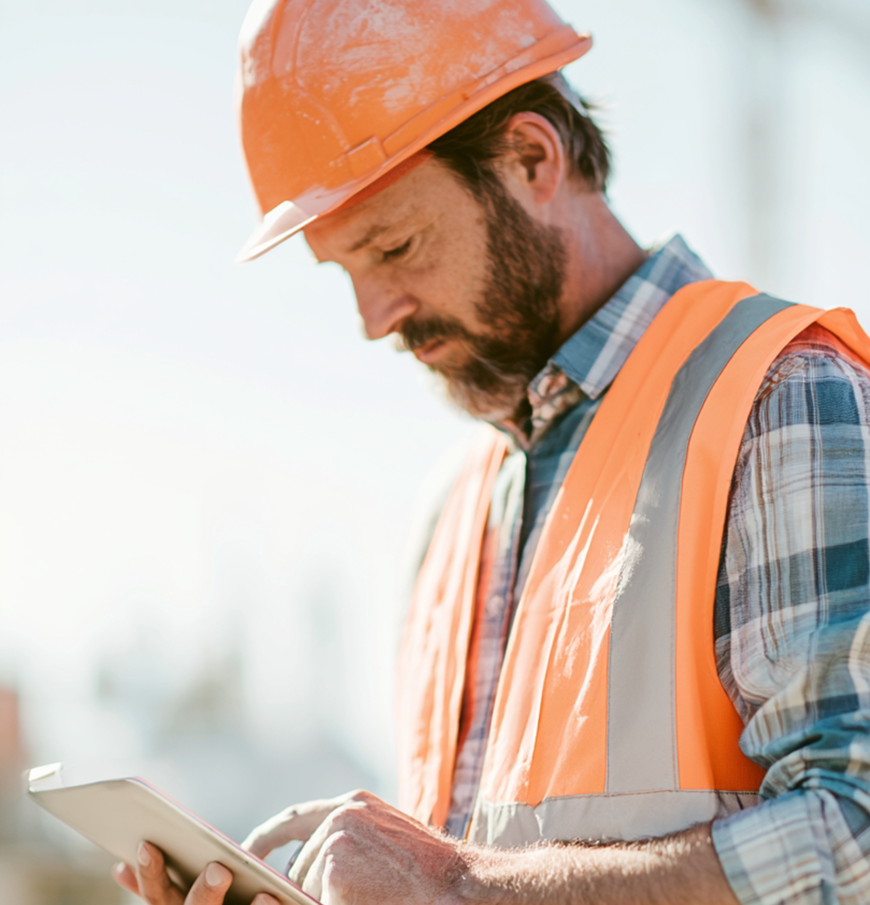 Construction professional reviewing field documentation on a tablet at a jobsite.